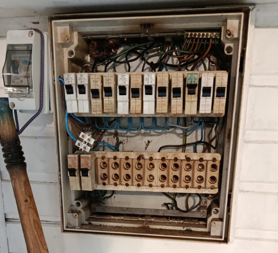 Ancien tableau électrique à fusibles, ouvert, câbles apparents, dans une maison visitée en Belgique
